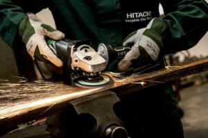 A skilled worker using an angle grinder on metal, producing sparks in an industrial workshop.